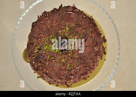 Delizioso cioccolato fresco Pistaccio torta con pezzetti di cioccolato intorno e pistacchi e servite sulla piastra di vetro con decorazione di Natale Foto Stock