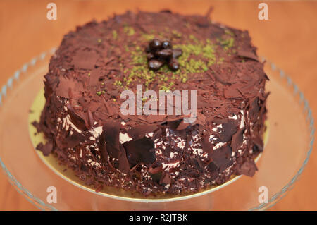 Delizioso cioccolato fresco Pistaccio torta con pezzetti di cioccolato intorno e pistacchi e servite sulla piastra di vetro con decorazione di Natale Foto Stock