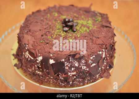 Delizioso cioccolato fresco Pistaccio torta con pezzetti di cioccolato intorno e pistacchi e servite sulla piastra di vetro con decorazione di Natale Foto Stock