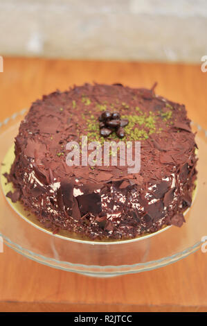 Delizioso cioccolato fresco Pistaccio torta con pezzetti di cioccolato intorno e pistacchi e servite sulla piastra di vetro con decorazione di Natale Foto Stock