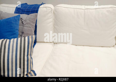 Interno del soggiorno con divano bianco con cuscini colorati e una coperta. Foto Stock