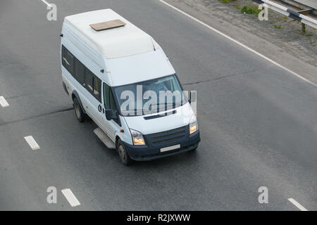 Piccolo bus bianco va in autostrada in sera Foto Stock