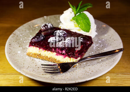 Cheesecake servita con panna. La cheesecake è guarnita con frutta e servito con la menta-sormontato crema. Foto Stock
