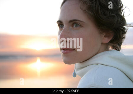 Giovane donna sulla spiaggia al tramonto Foto Stock