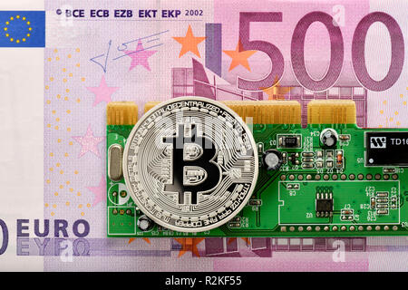 Immagine simbolica di valuta digitale, argento fisico moneta Bitcoin sulla banconota da 500 euro e il circuito stampato Foto Stock