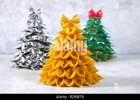 Come fare un albero di Natale da materie pasta conchiglie. Il processo per la realizzazione di alberi di Natale da pasta, piastre in cartone, colla a caldo e la vernice o spra Foto Stock