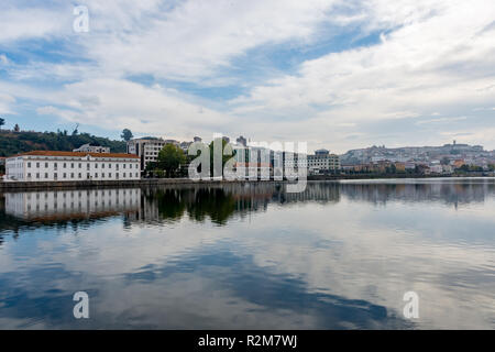 Nuvole e gli edifici lungo il fiume si riflette nel gin chiaro Rio Mondego a Sao Bartolomeu in Portogallo Foto Stock