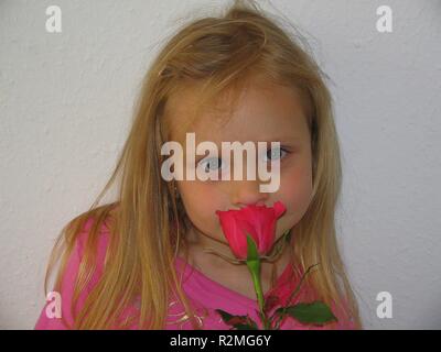 Ragazza odorare una rosa Foto Stock