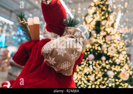 Santa da dietro con borsa regalo su sfondo bokeh di albero di natale. Foto Stock