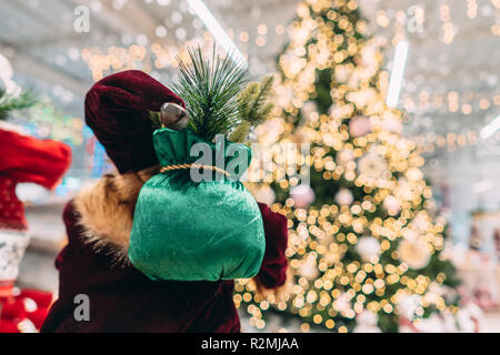 Santa da dietro con borsa regalo su sfondo bokeh di albero di natale. Foto Stock