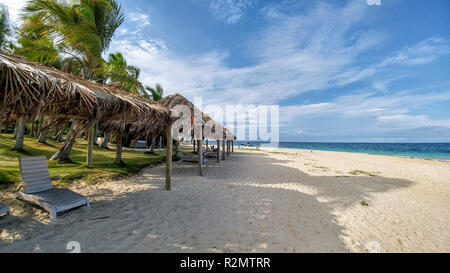 I lettini sulla spiaggia sotto i tetti di paglia dal mare, Isole Figi Foto Stock