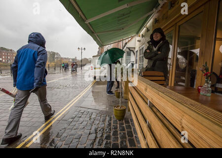 Bewdley, UK. Xx Novembre, 2018. Regno Unito: meteo su un terribilmente freddo giorno di novembre, con vento pungente e acquazzoni improvvisi, folk sono inclini a cercare riparo e vedere che cosa è in offerta presso i loro locali osteria. Una persona lascia, in attesa di pioggia per facilità mentre un giovane con ombrellone controllare il menu all'esterno. Credito: Lee Hudson/Alamy Live News Foto Stock