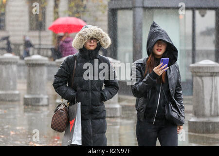 Due donne sono visti si ripara dalla pioggia sotto cappe su un freddo giorno. Secondo il Met Office, neve e grandine è prevista in Gran Bretagna questa settimana come temperature cadono. Foto Stock