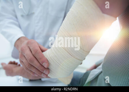 Ortopedico applicando un bendaggio sulla mano del paziente in clinica Foto Stock