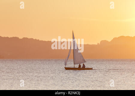 Barca a vela sul Chiemsee dietro di esso Alpi di Chiemgau, Übersee, Chiemgau, Alta Baviera, Baviera, Germania meridionale, Germania, Europa Foto Stock