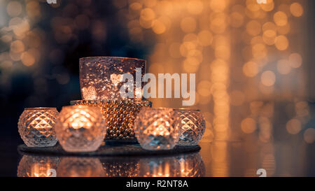 Arredamento interno accogliente casa, candele brucianti in occhiali con sfondo luci romantiche sfocate. Natale o inverno stagione autunno casa interiore Foto Stock