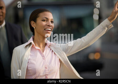 Sorridente metà donna adulta il sollevamento a mano per fermare un taxi in città. Foto Stock