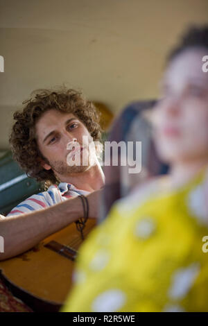 Giovane uomo di suonare una chitarra all'interno di un furgone. Foto Stock