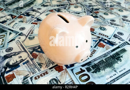 Salvadanaio su centinaia di dollari di banconote Foto Stock