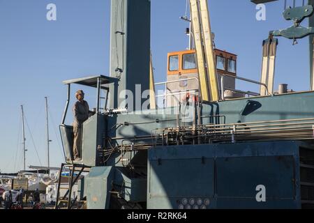 Matt Doster, un lavoratore di manutenzione ad una barca commerciale-fissaggio company, aziona una gigantesca porta di sollevamento "Oscar", un 75-piede mechanized landing craft azionato da U.S. I marinai della marina militare assegnato alla Marina Molo al Marine Corps Air Station Cherry Point, N.C., Ottobre 31, 2018. La nave fu oggetto di manutenzione in una barca mercantile cantiere nei pressi di Beaufort, N.C., in grado di sollevare il recipiente dall'acqua per lo scafo ed elica di manutenzione. Cirripedi erano sabbiato al di fuori del lato inferiore per diminuire la resistenza in acqua, la carena è stata ispezionata per verificare la presenza di spaccature o ammaccature, che sono stati fissati e vernice speciale è stata applicata Foto Stock