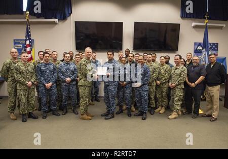 OAK HARBOR, nello Stato di Washington (Nov. 7, 2018) della Cmdr. William Palmer, comandante della flotta Centro Readiness (FRC) Northwest, presenta il livello Gold Award per i sistemi di gestione della sicurezza (SMS) di aviazione di Boatswain Mate (attrezzature) 1a classe Henry Larreynaga e il resto del team di sicurezza a Naval Air Station (NAS) Whidbey Island. FRC Northwest guadagnato il livello Oro riconoscimento per il suo programma di SMS diventando il primo FRC il comando della marina militare di ricevere una tale distinzione. Foto Stock