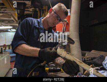 Le ACQUE AL LARGO DELLA COSTA DI SAIPAN (nov. 09, 2018) Fireman Cody Shue utilizza una smerigliatrice per rimuovere il materiale in eccesso da una linea di combustibile per le riparazioni all'interno dello scafo tecnico di manutenzione shop del dock anfibio sbarco nave USS Ashland (LSD 48). Marinai e Marines dalla Ashland, assegnato al comandante, squadrone anfibio 11, sono fornendo il Dipartimento della Difesa sostegno alla Repubblica della Mariana Islands settentrionale' civile e funzionari locali come parte del FEMA-supportato Typhoon Yutu gli sforzi di recupero. Foto Stock