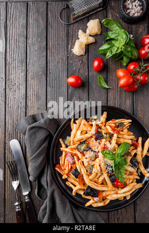 Fusilli al ferro la pasta con la salsa di pomodoro, pomodori, melanzane, la cipolla e il pepe su una piastra. Vista superiore Foto Stock