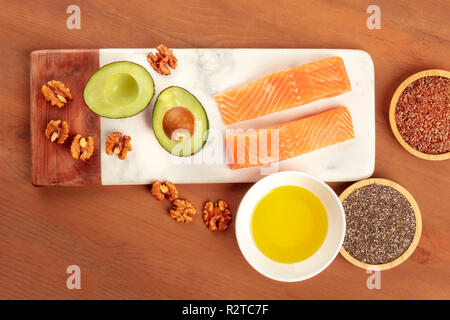 Una sana omega 3 la dieta alimentare. Salmone crudo, avocado, noci, chia e semi di lino, ripresa dall'alto su una scuri in legno rustico sfondo con un posto per te Foto Stock