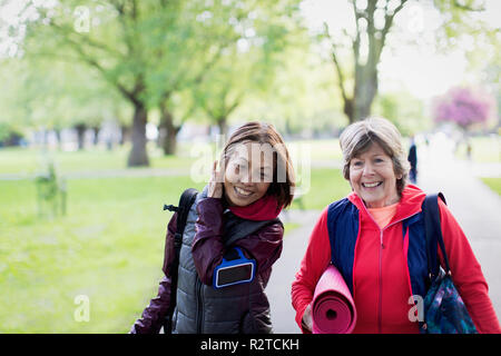 Attiva le donne senior amici con materassino yoga passeggiate nel parco Foto Stock