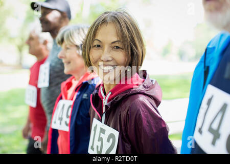 Ritratto sorridente e fiducioso senior attiva donna alla gara sportiva sulla linea di partenza Foto Stock