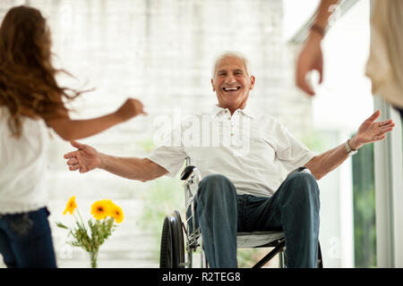 Senior uomo in sedia a rotelle, saluto i suoi nipoti. Foto Stock