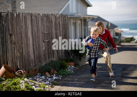 Due fratelli giocare con un calcio sulla strada. Foto Stock