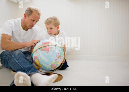 Padre guardando un globo del mondo con il suo figlio. Foto Stock