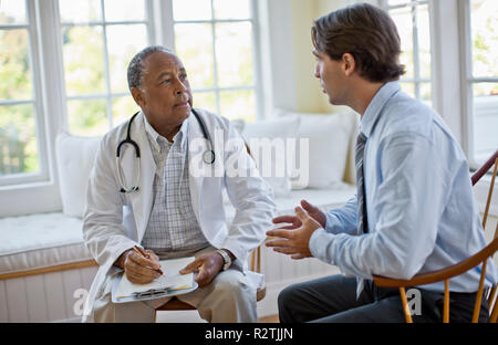 Metà uomo adulto a parlare con il suo medico maturo. Foto Stock
