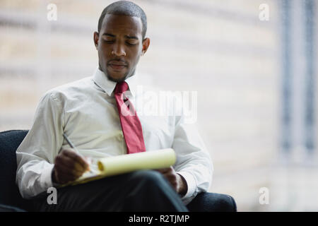Metà-imprenditore adulti citando con un blocco note in una stanza. Foto Stock