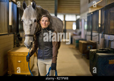 Ritratto di una metà donna adulta e il suo cavallo in una stalla. Foto Stock