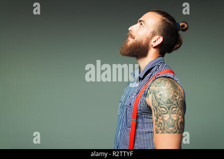 Curioso hipster l uomo con la barba e la spalla tattoo cercando Foto Stock