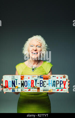 Ritratto felice donna senior holding non preoccupatevi di essere felice di targhe Foto Stock