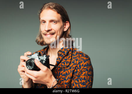 Ritratto fiducioso giovane uomo con i baffi manubrio tenendo la fotocamera retrò Foto Stock