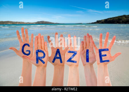 Molte mani la costruzione di parola italiana Grazie significa Grazie. Bellissima spiaggia, oceano e mare come sfondo Foto Stock