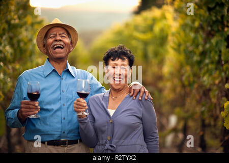 Molto felice coppia senior di bere il vino rosso in vigna. Foto Stock