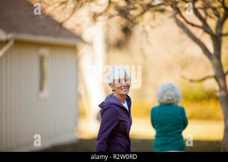 Ritratto di una sorridente donna senior a spasso con gli amici in un parco. Foto Stock