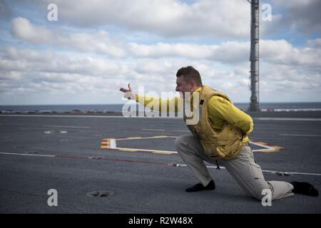 Oceano atlantico (nov. 10, 2018) Lt. La Cmdr. Ty Fritz, dalla Easton, Maryland, dà il segnale per lanciare i suoi stivali da la catapulta a bordo della portaerei USS George H.W. Bussola (CVN 77). Navy catapulta ufficiali tradizionalmente lanciare gli scarponi al termine di una tournée di successo. GHWB è in corso nell'Oceano Atlantico conduzione di routine di esercizi di allenamento per mantenere la disponibilità del gestore. Foto Stock