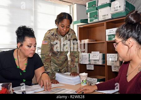 FORT BLISS, Texas - Spc. Ashley Lubo, una specialista risorse umane per il 210th regionale gruppo di supporto, Aguadilla, Puerto Rico e sottufficiale in carica della mobilitazione e la distribuzione della brigata sezione di transizione, conferisce con transizione conduce Patricia Sierra (sinistra) e Bertha Dennis durante la mobilitazione unità/smobilitazione processi nella sezione di transizione del MaD brigata, direzione dei piani, di formazione, di mobilitazione e di sicurezza a Fort Bliss, Texas, il 31 ottobre 2018. La sezione di transizione è responsabile di garantire la precisione e l'autenticazione per la Guardia Nazionale e rese Foto Stock