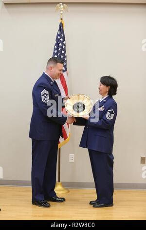 Alaska Air Guard comando Master Chief Sgt. James Wolverton, 168a comando parafango chief, presenta AKANG Master Sgt. Ella Doak, anche con l'ala 168a, con un tradizionale Alaskan coppa d'oro con inciso il suo date di servizio durante la sua cerimonia di pensionamento in Kipnuk, Alaska, nov. 9, 2018. Doak hanno optato per la cerimonia nella sua città natale dopo più di 24 anni di servizio dedicato per lo stato e la nazione. Foto Stock