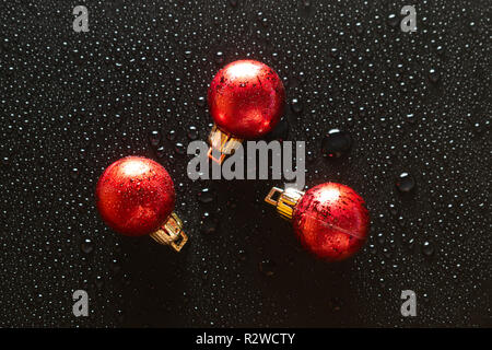 Globo di natale su sfondo nero coperta con spruzzi di acqua Foto Stock