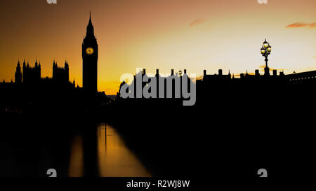 Silhouette vista del Palazzo del Parlamento e il Big Ben Tower a Londra con un cielo giallo al tramonto. Formato panoramico. Foto Stock