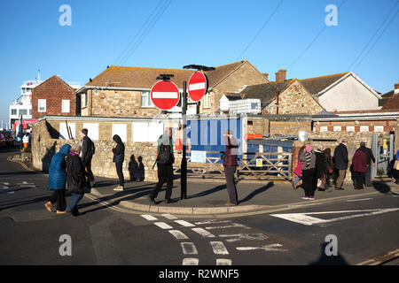 Escursionisti visita Yarmouth Isle of Wight attraversando la strada e al terminal del traghetto in condizioni soleggiate in un giorno Foto Stock