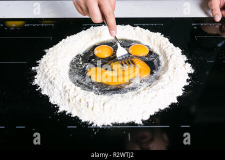 Lo Chef prepairing di sfoglia di pasta fresca su una superficie nera Foto Stock