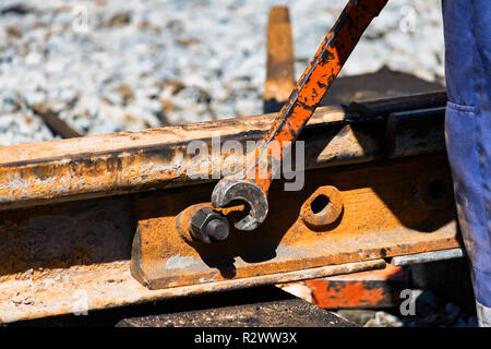 Lavoratore si stringe il skrew in linea ferroviaria o i binari del tram Foto Stock